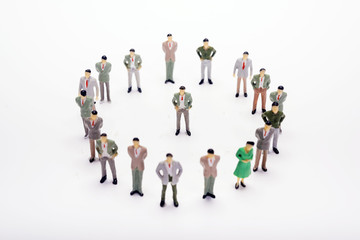Miniature business people standing in circle over backdrop or background.