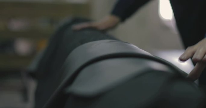 Worker beautifully stacks black leather on pallets