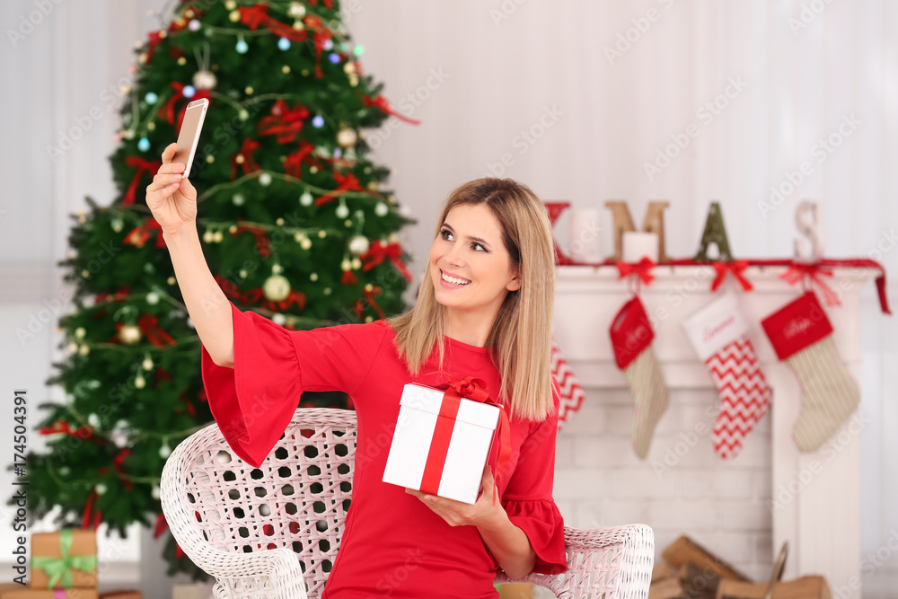 Wall mural young beautiful woman taking selfie in room decorated for christmas