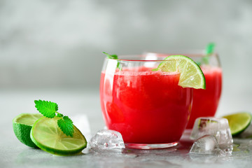 Glass of fresh watermelon juice with lime, mint, ice on light background, copy space