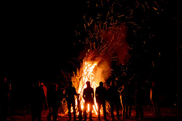 People stand near a big fire at night