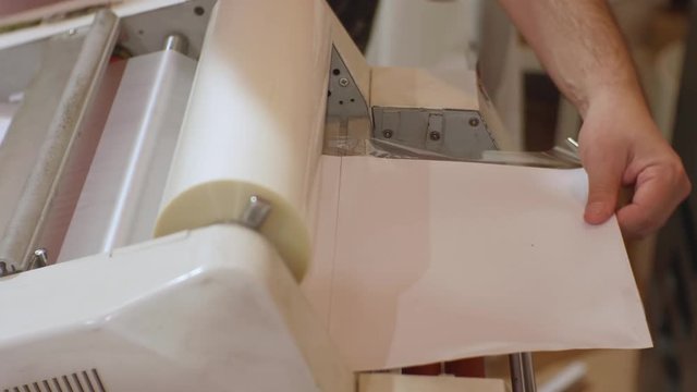 White male working with roll laminator.