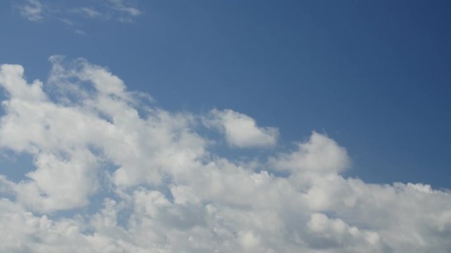 Time lapse clip of white fluffy clouds over blue sky. Copy space.