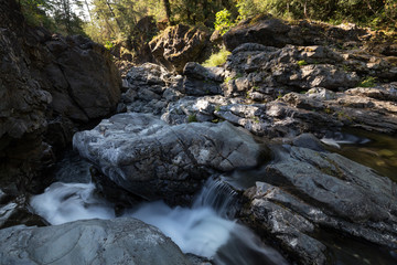 Fototapeta premium Water spring running down the smooth rocks in a beautiful canyon. Taken in Sooke Potholes Provincial Park near Victoria, Vancouver Island, BC, Canada. 