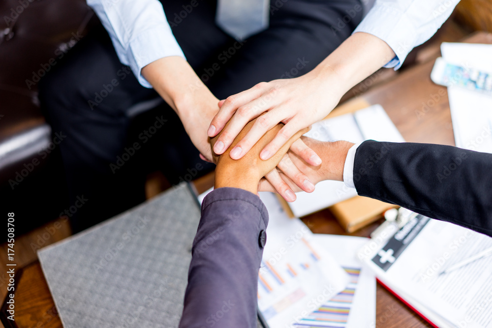 Wall mural close up top view of business people putting their hands together, unity and teamwork concept