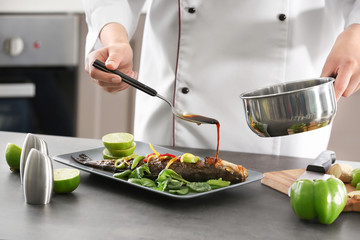 Chef pouring fish with delicious sauce in restaurant