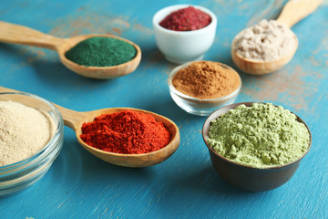 Kitchenware with different colorful superfood powders on wooden table
