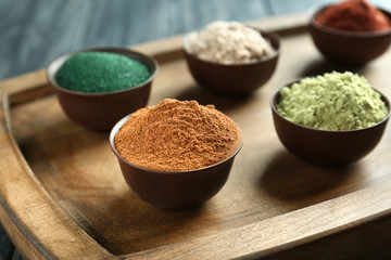 Different colorful superfood powders in bowls on wooden board