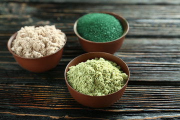 Different colorful superfood powders in bowls on wooden table