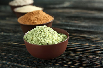Different colorful superfood powders in bowls on wooden table