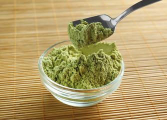 Superfood powder in bowl and spoon on table