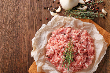 Parchment paper with fresh minced meat on wooden board