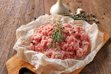 Parchment paper with fresh minced meat on wooden board