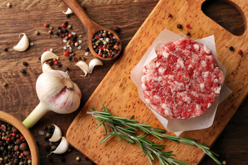 Parchment paper with fresh minced meat on wooden board