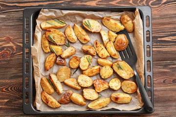 Baking tray with delicious rosemary potatoes on table