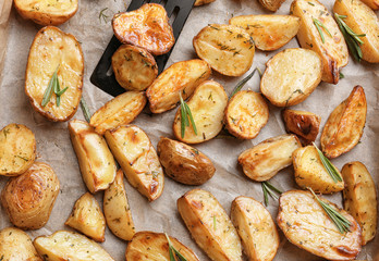 Delicious baked potatoes with rosemary on parchment, closeup
