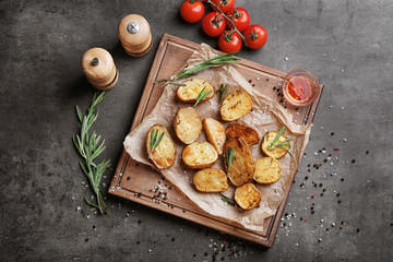Board with delicious rosemary potatoes on table