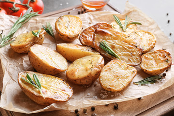 Board with delicious rosemary potatoes on table