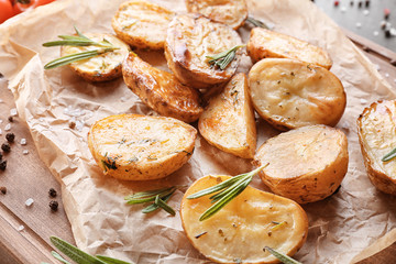 Delicious baked potatoes with rosemary on parchment, closeup
