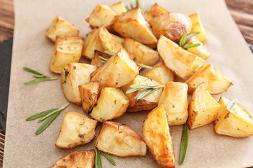Delicious baked potatoes with rosemary on parchment, closeup