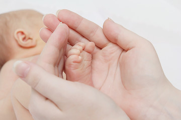 Obraz na płótnie Canvas baby's leg in female hands