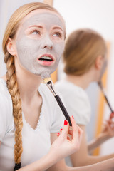 Woman with grey clay mud mask on her face