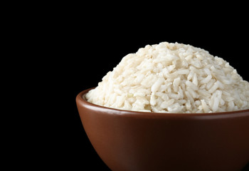 Bowl with brown rice on black background, close up