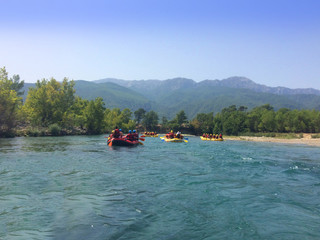 A group of men and women are rafting on the river, extreme sport. Tourists-extremals rowing in a boat, mobile photo
