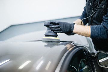 Car detailing - Hands with orbital polisher in auto repair shop. 