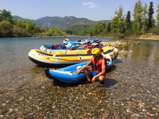 A young man squatting near an inflatable boat rafting along a mountain river