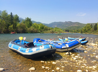 Fototapeta premium Inflatable boats (rafts) for rafting along a mountain river in front of a beautiful scenery