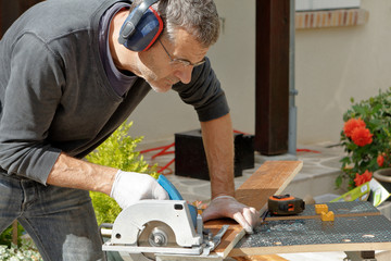 homme scie une planche de bois