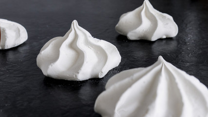 Sweet white meringue is isolated on a dark background.