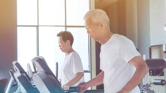 Healthy Asian senior couple exercise together in gym running treadmill