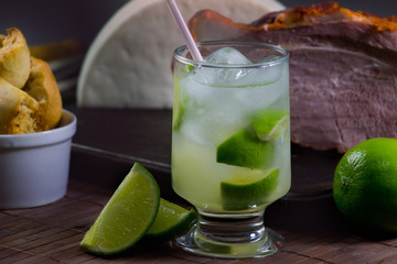 Caipirinha acompanhada de petiscos encima de uma mesa de madeira 