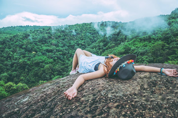 Asian women travel relax in the holiday. Sleep on a rocky cliff. Wild nature wood on the mountain.