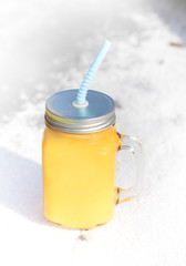 Winter vitamins immunity concept . Freshly squeezed Orange citrus juice for health in glass jar on snow.