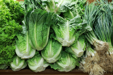 Variety of fresh green salads and onions in the grocery store.