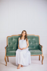 Young happy pregnant woman sitting on sofa