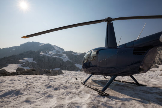 Helicopter landed on the snow in the mountains during a sunny summer day. Taken near Vancouver, BC, Canada.