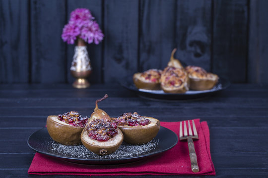 Homemade baked pears with cottage cheese, honey, red cranberries and walnuts in black plate, close up