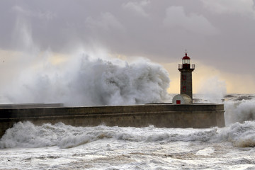 Big wave against lighthouse at sunset