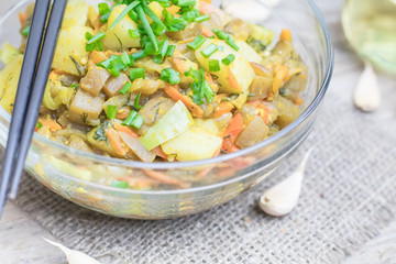 Homemade nutritional vegetable ragout in glass plate bowl on rustic old wooden table. Vegan or vegetarian food diet. Selective focus.
