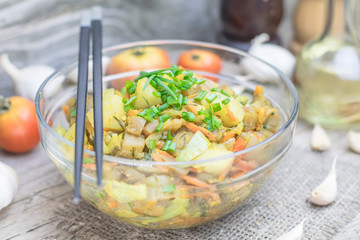 Homemade nutritional vegetable ragout in glass plate bowl on rustic old wooden table. Vegan or vegetarian food diet. Selective focus.