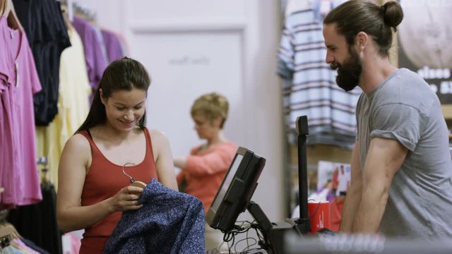 Customer shopping in clothing store goes to register to make a purchase