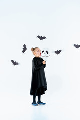 Little girl witch in black dress over magical accessories. Halloween, the studio evening.
