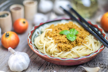 Soy vegan protein marinara spaghetti pasta in ceramic bowl with chopsticks on wooden background. Protein albumen source. Vegan vegetarian nutritional food.