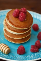 Delicious pancakes with raspberries and honey in a bowl 
