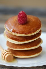 Delicious pancakes with raspberries and honey in a bowl 