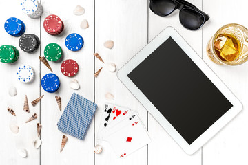 Gambling. Poker chips, cards and the dice nearby tablet on wooden table. Top view. Copyspace. Poker